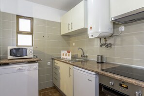 A compact kitchen with a microwave, dishwasher, sink, and stove.