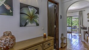 Um corredor com um armário de madeira, um quadro de uma flor e uma porta que dá para uma varanda.
