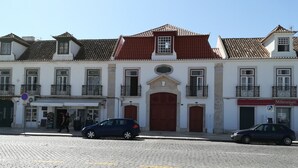 Un bâtiment historique avec un toit recouvert de tuiles rouges, des murs blancs et de nombreuses fenêtres.