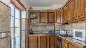 Une cuisine avec des meubles de rangement en bois, une cuisinière, un four à micro-ondes et une fenêtre.