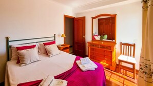 Une chambre à coucher avec un lit, une commode, une chaise et un miroir.