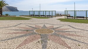A paved area with a star-shaped pattern, benches, and a view of the sea.