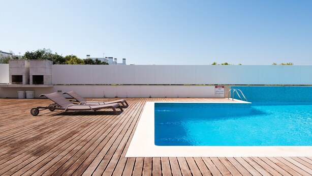 Ein Pool auf dem Dach mit Holzterrasse und Liegestühlen.