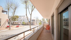 Ein Balkon mit Metallgeländer, der auf eine Straße mit Bäumen und Gebäuden blickt.