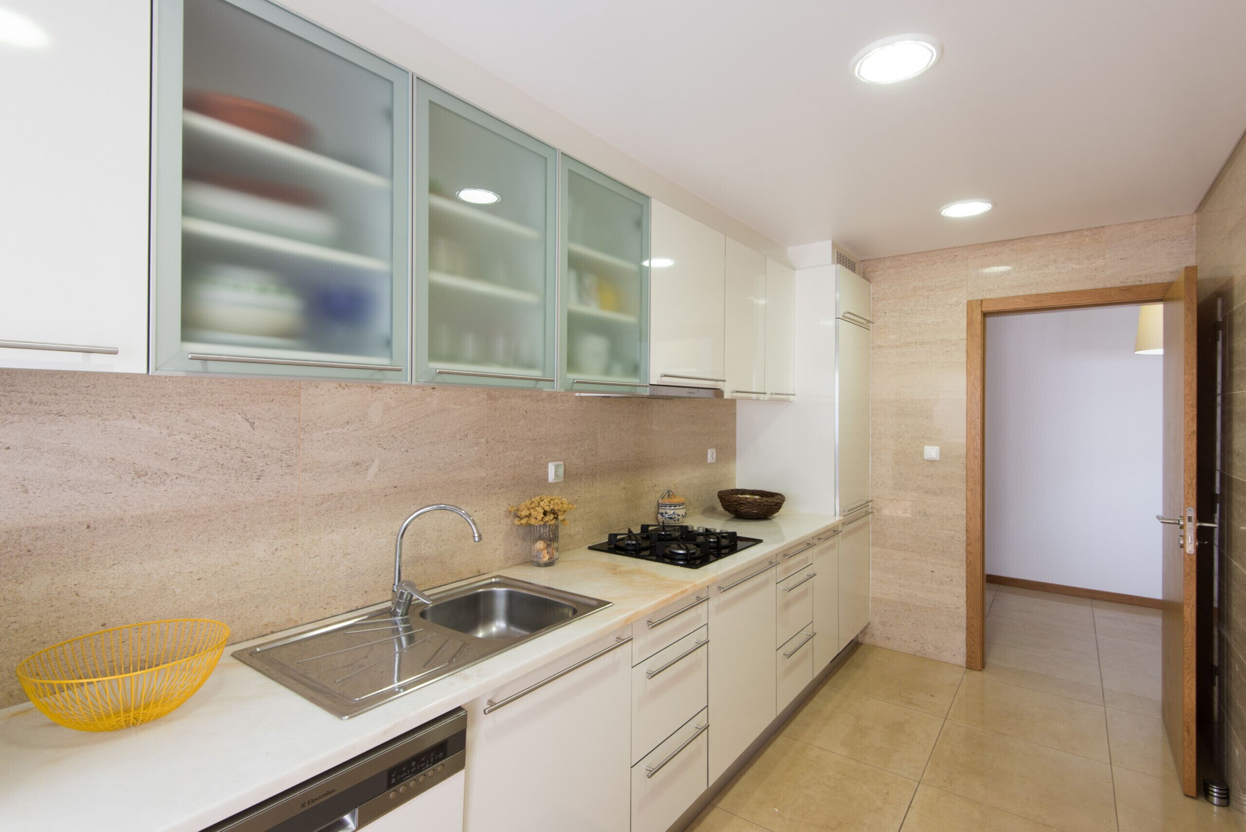 A modern kitchen with white cabinets, a stainless steel sink, and a built-in stove.