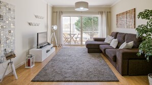 Uma sala de estar moderna com sofá, televisão e uma grande janela.