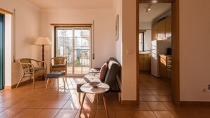 A living room with a sofa, two chairs, a small table, and a lamp. There is a sliding glass door leading to a balcony. - FLH Armação de Pêra Ocean View Flat (Armação de Pêra)