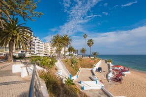 A coastal hotel with a beachside terrace, palm trees, and a clear view of the sea. - FLH Armação de Pêra Ocean View Flat (Armação de Pêra)