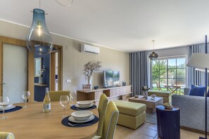 Un salón moderno con comedor, un sofá, un televisor y vistas al exterior.
