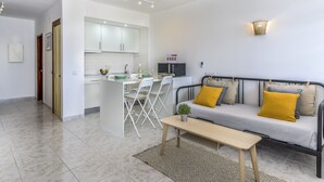 Ein modernes Wohnzimmer mit einer Couch, einem Couchtisch und einem Essbereich mit Stühlen und einer kleinen Kücheninsel.