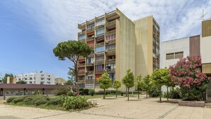 Ein mehrgeschossiges Wohnhaus mit Balkonen, umgeben von einem angelegten Innenhof mit Bäumen und Sträuchern.