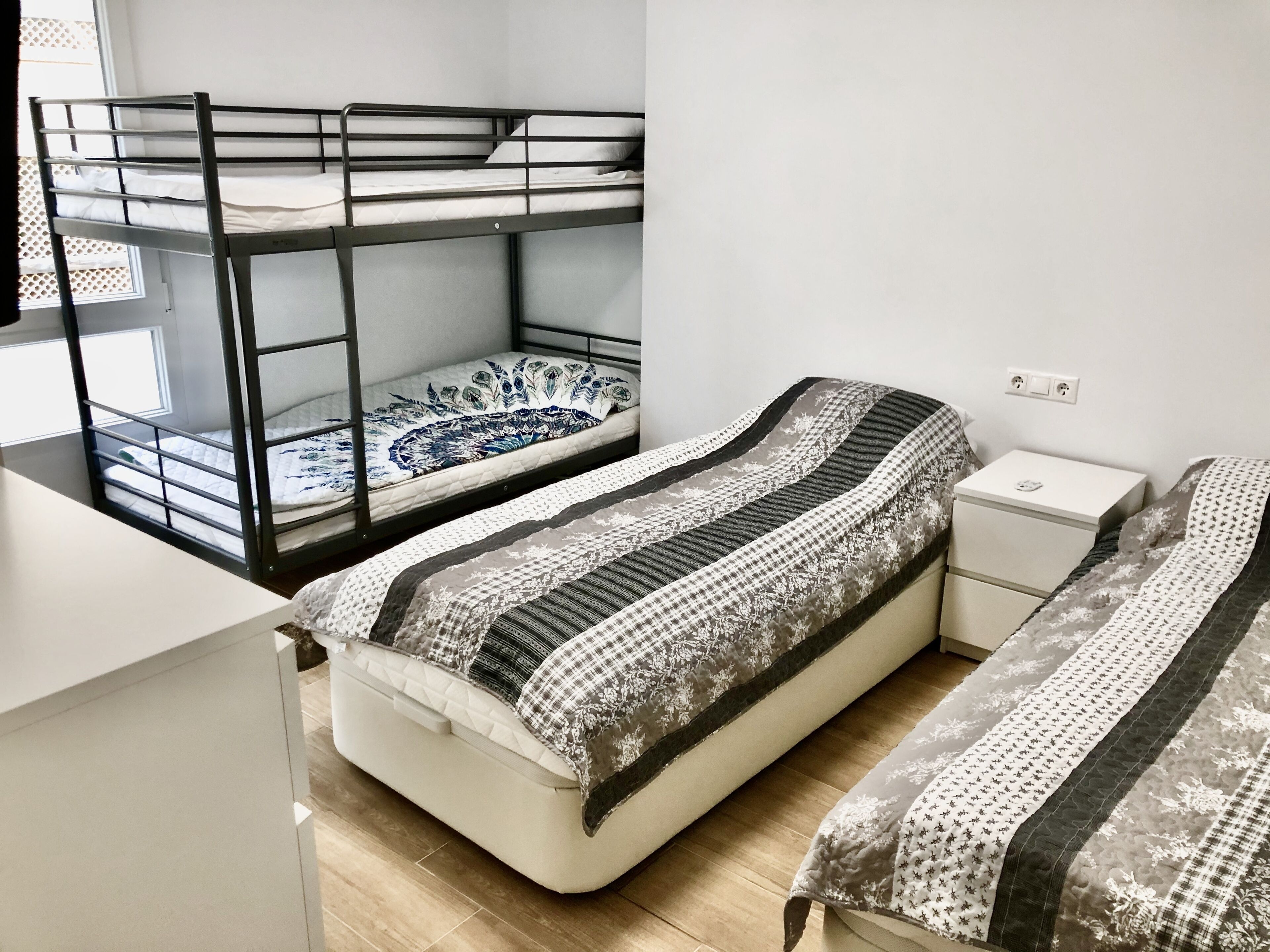 A dorm-style room with bunk beds, a desk, and a nightstand.