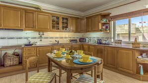 Una cucina con mobili in legno, un tavolo da pranzo con stoviglie gialle e una finestra con vista.