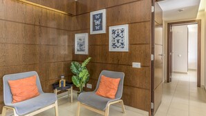 A room with two grey chairs with orange cushions, a small table with a plant, and framed artwork on the wall. - FLH Salgados Beach Apartment (Albufeira)