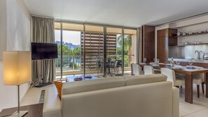 A modern hotel room with a living area, dining space, and a balcony with a view of the city. - FLH Salgados Beach Apartment (Albufeira)