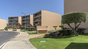 A modern building with multiple balconies, a paved walkway, and well-maintained greenery. - FLH Salgados Beach Apartment (Albufeira)