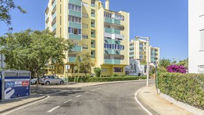Un immeuble résidentiel à plusieurs étages, doté de balcons, d’un espace de stationnement et de boîtes aux lettres.