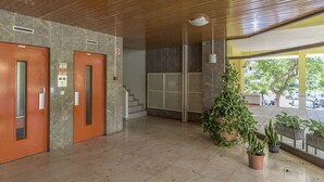 Un hall d’entrée avec deux portes en bois, un escalier et des plantes en pot.