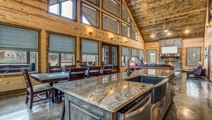A spacious kitchen with a granite countertop, wooden cabinets, and a stone backsplash. - Enjoy Pier on a Pond, Hot Tub, Playset, Games, Outdoor Furniture, Fireplace, TV (Broken Bow)