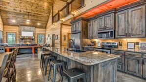 A spacious kitchen with granite countertops, stainless steel appliances, and wooden cabinetry. - Enjoy Pier on a Pond, Hot Tub, Playset, Games, Outdoor Furniture, Fireplace, TV (Broken Bow)