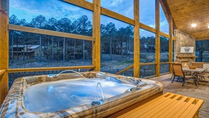 A wooden cabin with a hot tub, large windows, and a stone fireplace. - Enjoy Pier on a Pond, Hot Tub, Playset, Games, Outdoor Furniture, Fireplace, TV (Broken Bow)