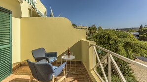 A balcony with two chairs and a small table, a bottle of wine, and a view of the surrounding landscape. - FLH Praia da Luz Apartment with Pool (Lagos)