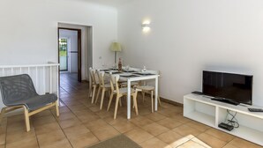 A dining area with a white table, chairs, and a television on a stand. - FLH Praia da Luz Apartment with Pool (Lagos)