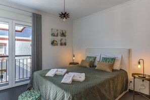 A hotel room with a large bed, a balcony, and a view of the building.