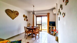 Un comedor con mesa y sillas, televisor y balcón con vistas.