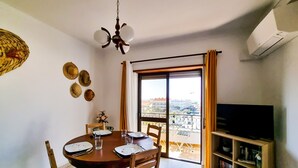 Comedor con una mesa dispuesta para cuatro, ventilador de techo y una estantería llena de libros.