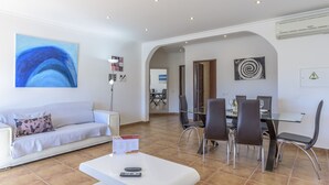 A modern living room with a sofa, a glass dining table, and a coffee table. - FLH Albufeira Vila Mira Flat with Pool (Albufeira)