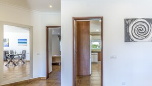 A spacious hallway with a dining area visible through a glass door, leading to a kitchen area. - FLH Albufeira Vila Mira Flat with Pool (Albufeira)