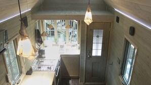 A compact kitchen with wooden walls, a central island, and pendant lighting.