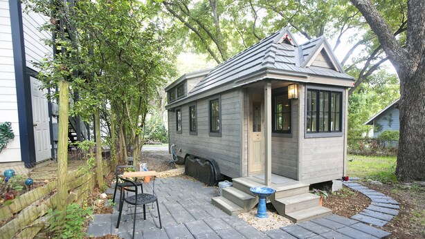 A small wooden cabin with a porch, a chair, and a table outside.