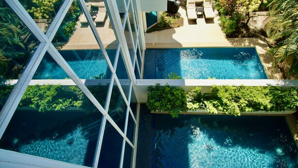 A rooftop pool area with multiple swimming pools, surrounded by lounge chairs and greenery. - Two Adjacent Gated Partial Ocean View Villas (Tamarindo)