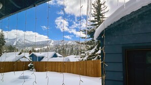 Ein Holzzaun, ein mit Schnee bedecktes Dach und eine Bergkulisse.