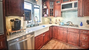A kitchen with wooden cabinets, stainless steel appliances, and a chalkboard with motivational writing.
