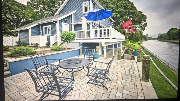 A house with a patio area featuring outdoor furniture and a blue umbrella.