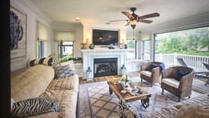 A spacious living room with a fireplace, comfortable seating, and a large TV.