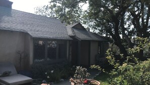A house with a sloped roof, a covered porch, and a garden with potted plants.