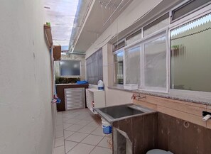 Cozinha estreita com pia, janela e bancada pequena.