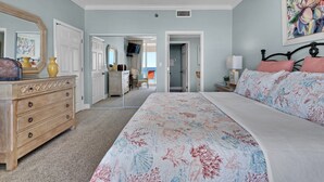 Un dormitorio con una cama grande, un aparador, un espejo y una puerta que da a otra habitación.
