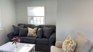 A living room with a grey sofa, a white coffee table, and a beige armchair. - Late August and fall dates available! (Dennis)