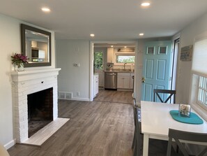Cozy living space with a fireplace, dining area, and kitchen, offering a view of the outdoors.