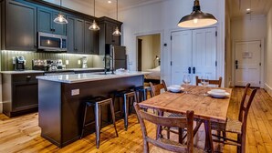 A modern kitchen with dark cabinetry, a central island, and pendant lighting.