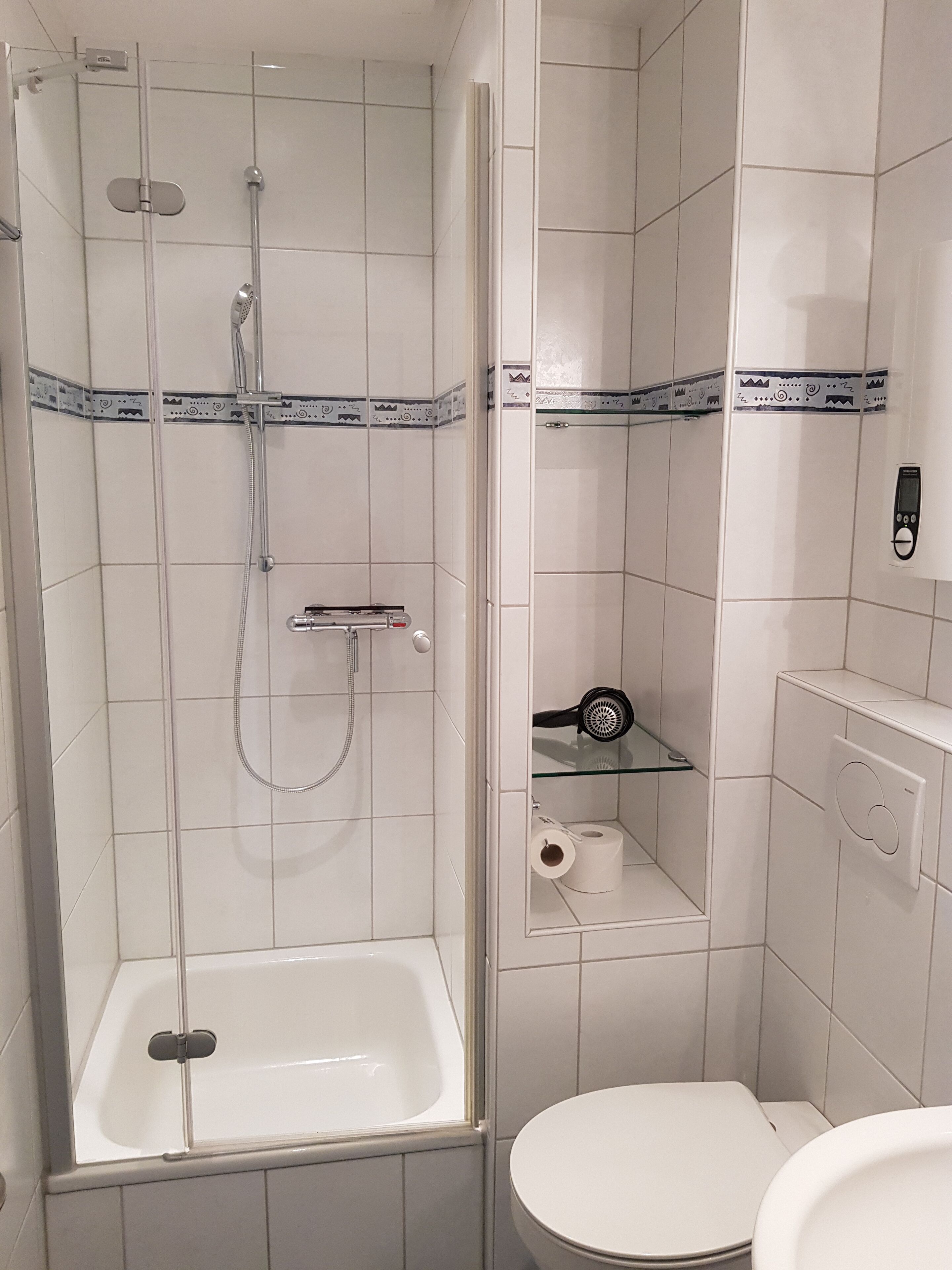 A bathroom with a glass-enclosed shower, a white bathtub, and a toilet.