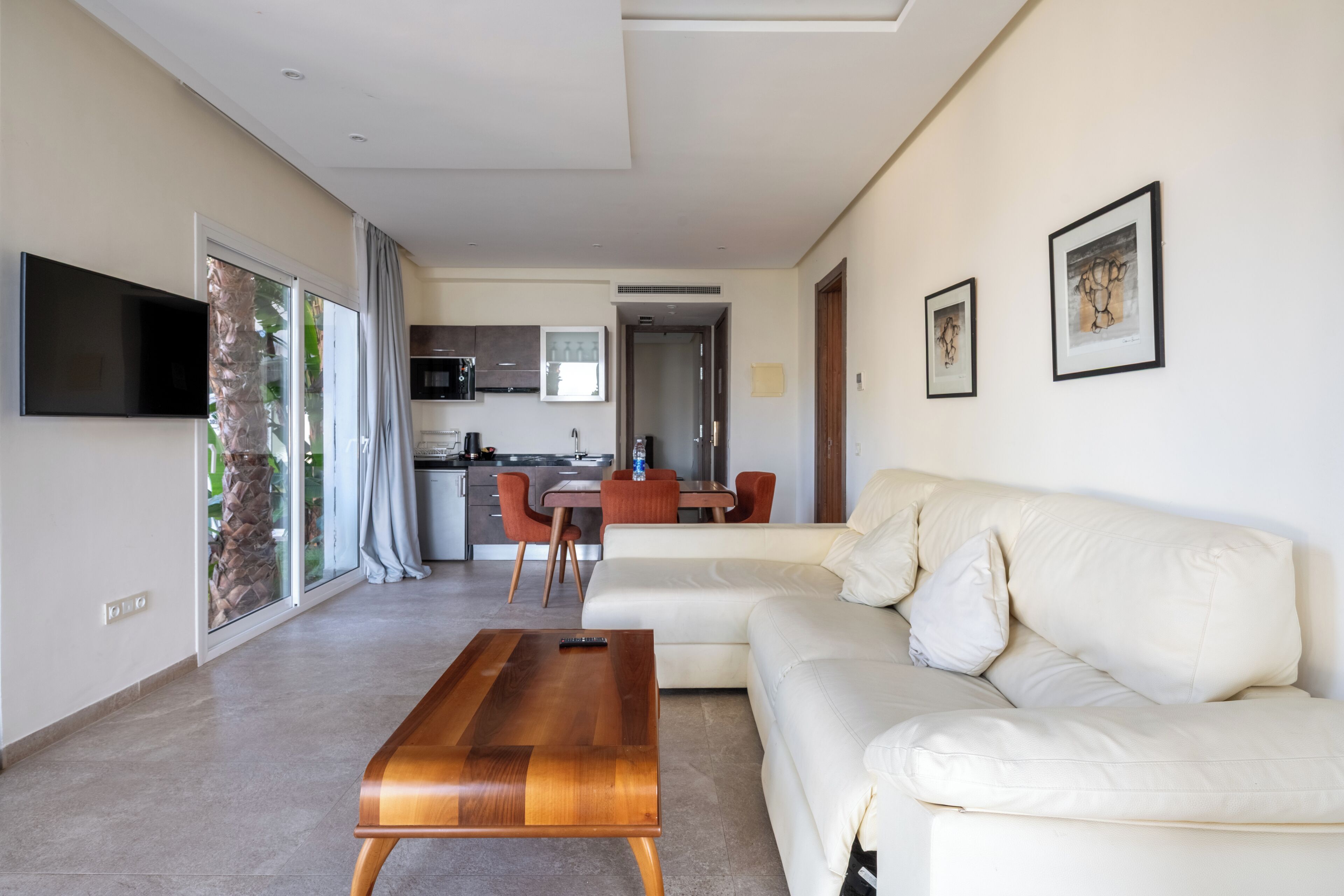 A modern living room with a sofa, a wooden coffee table, and a TV mounted on the wall.