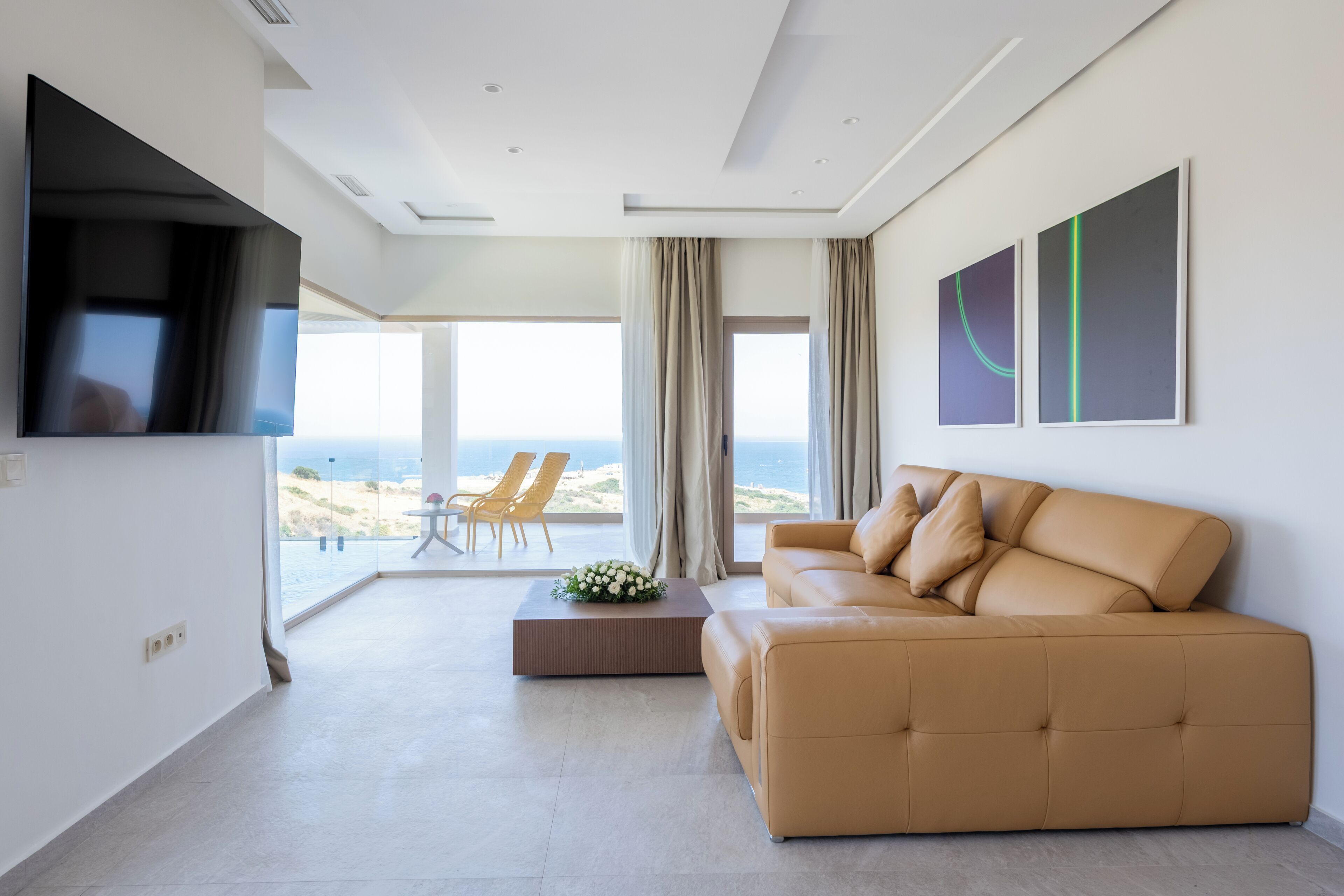 Un salón moderno con sofá, televisor de pantalla plana y vistas a la playa.