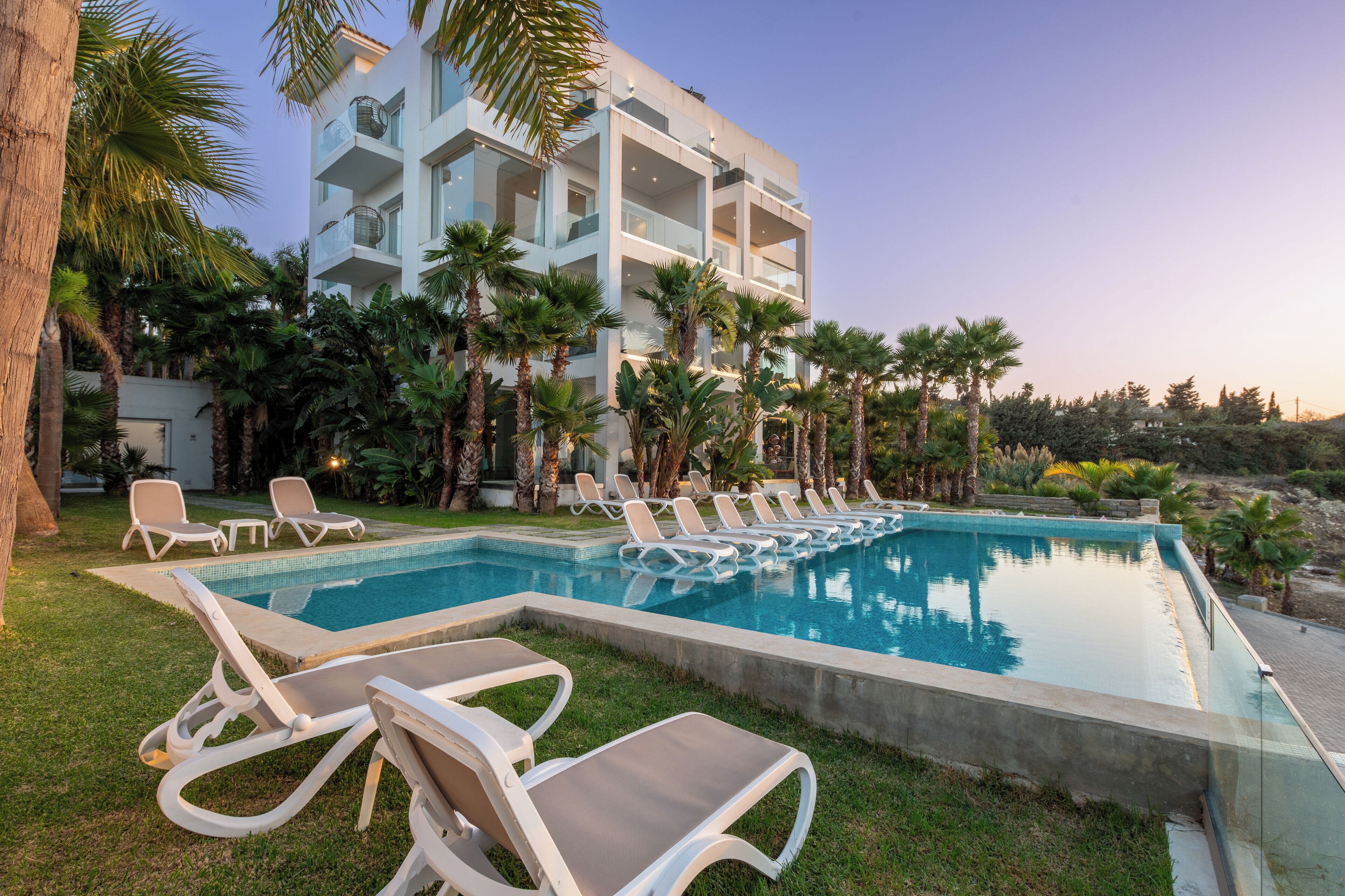 A pool area with lounge chairs and a modern building in the background.