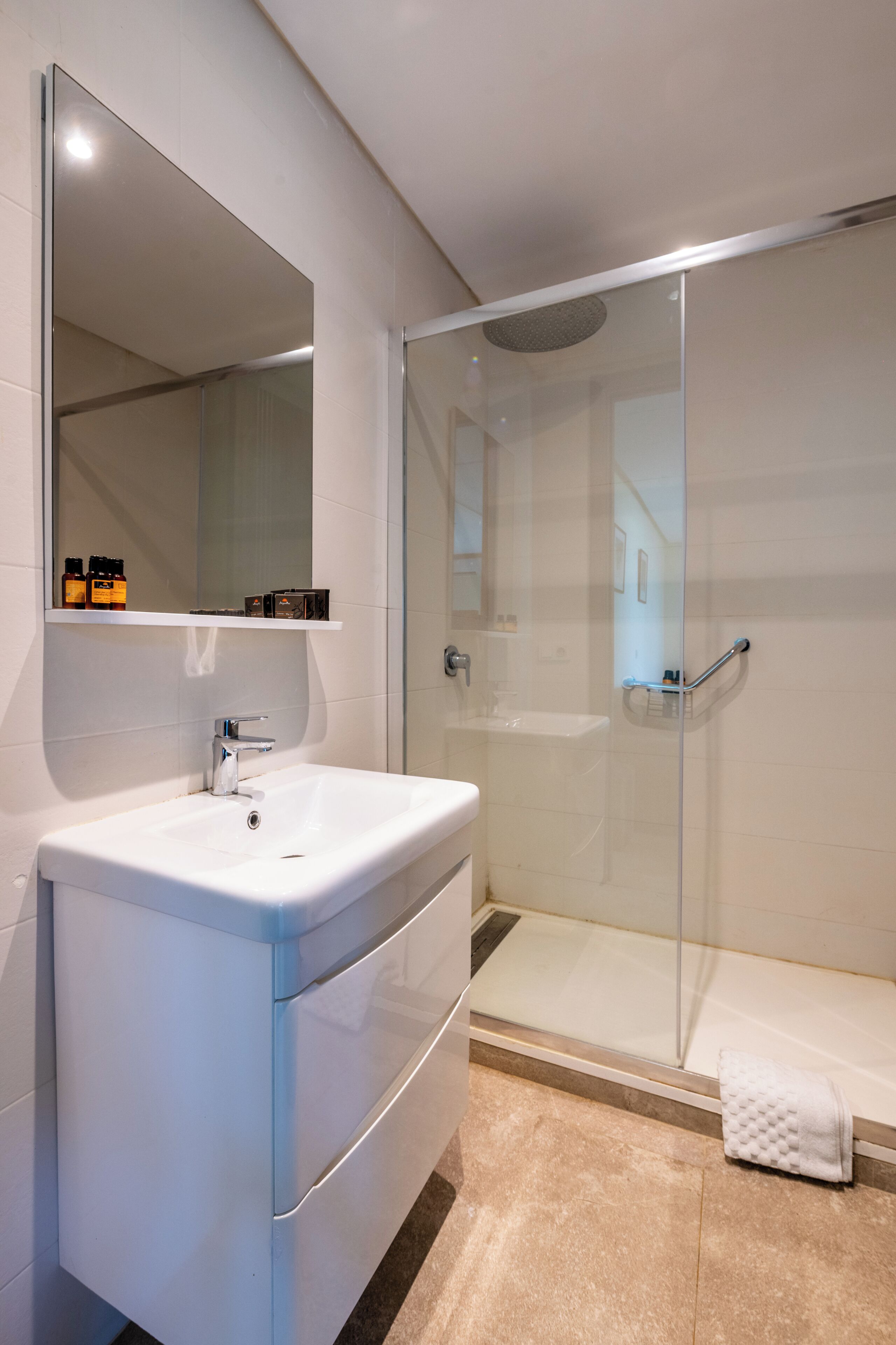 A modern bathroom with a white sink, a glass shower enclosure, and a mirror above the sink.